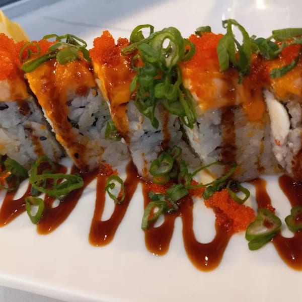 Zato Thai Cuisine & Sushi Bar's sushi roll with orange roe, green onions, and brown sauce drizzle.