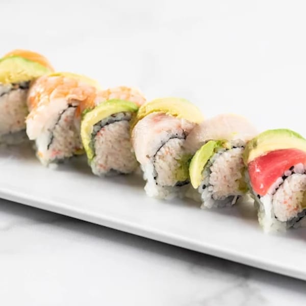 A row of Zato Thai Cuisine & Sushi Bar's colorful sushi rolls with various toppings on a white plate.