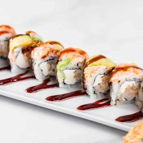 A row of Zato Thai Cuisine & Sushi Bar's shrimp and avocado sushi rolls with sauce.