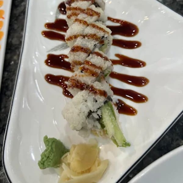 Zato Thai Cuisine & Sushi Bar's sushi roll with sauce, wasabi, and ginger on a white plate.