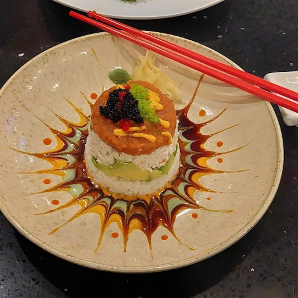 Zato Thai Cuisine & Sushi Bar's sushi tower with avocado, crab, tuna, caviar, and red chopsticks.