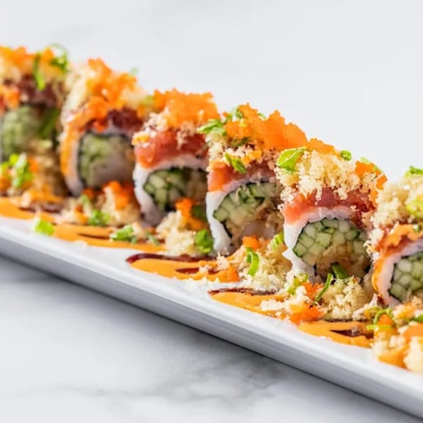 Zato Thai Cuisine & Sushi Bar's sushi rolls with tuna, cucumber, roe, and sauce on a white plate.
